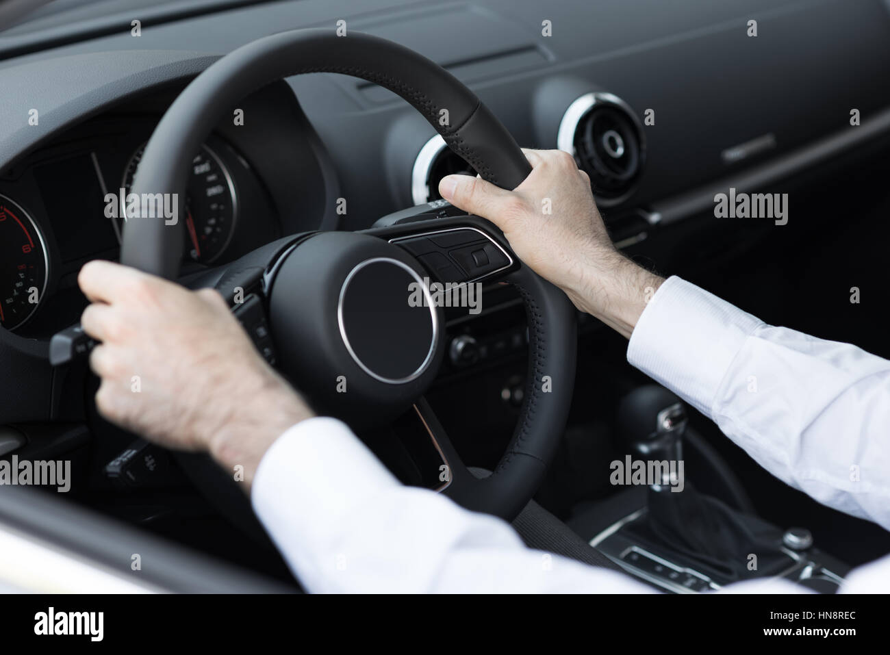 Successful businessman driving his car, hands on steering wheel close up Stock Photo