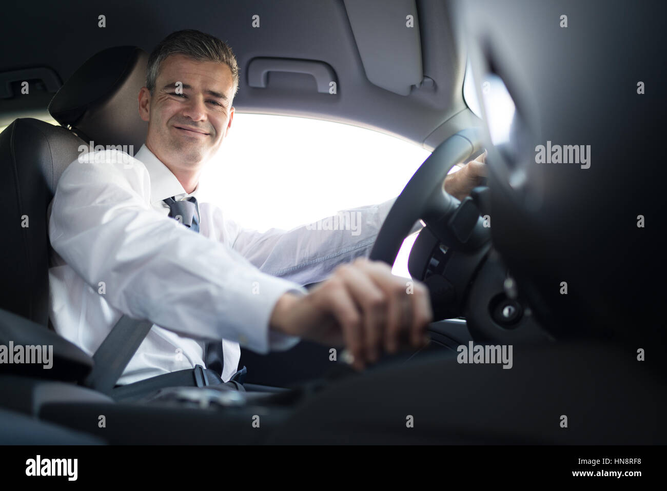 Confident smiling businessman driving to work with his brand new car