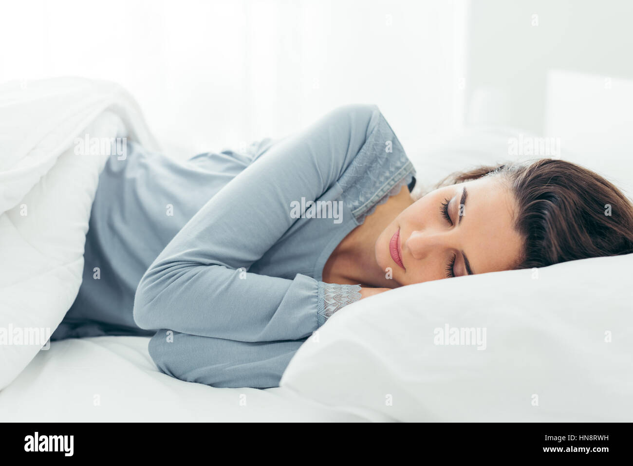 Young beautiful woman sleeping in her bed and relaxing in the morning Stock Photo