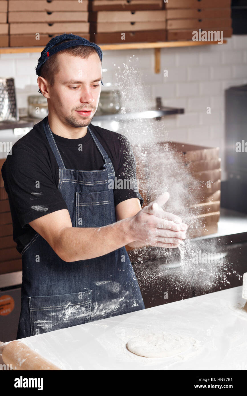 Roll out the dough. expanding cloud of flour. Closeup hand of chef