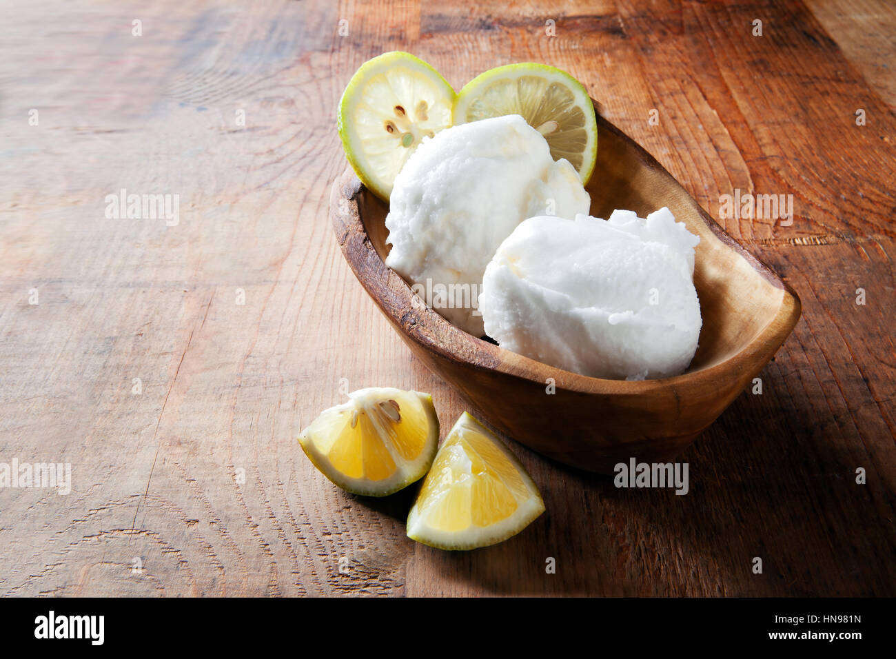 lemon sorbet in a wooden bowl from the olive tree to the table. and fresh lemons Stock Photo
