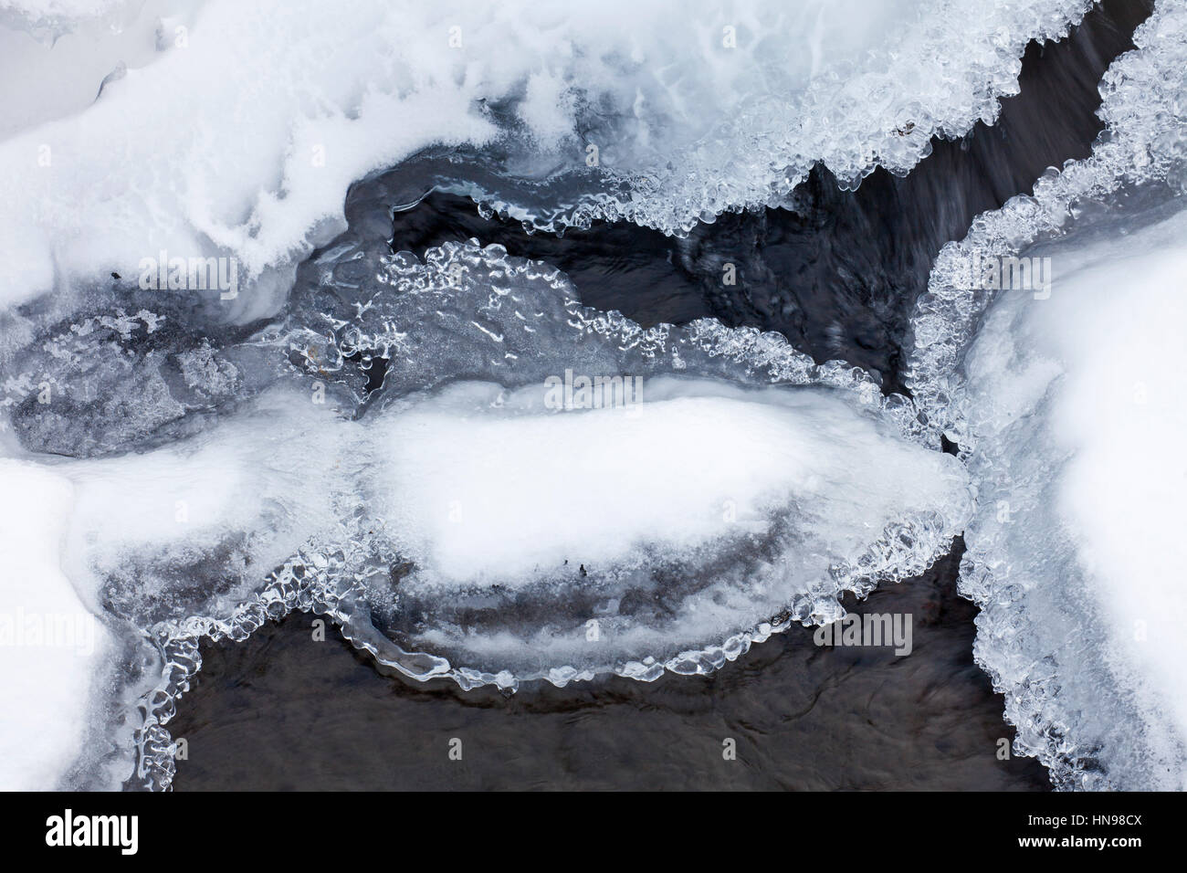 Ice formations formed by frost and freezing cold temperatures over running water of stream Stock Photo