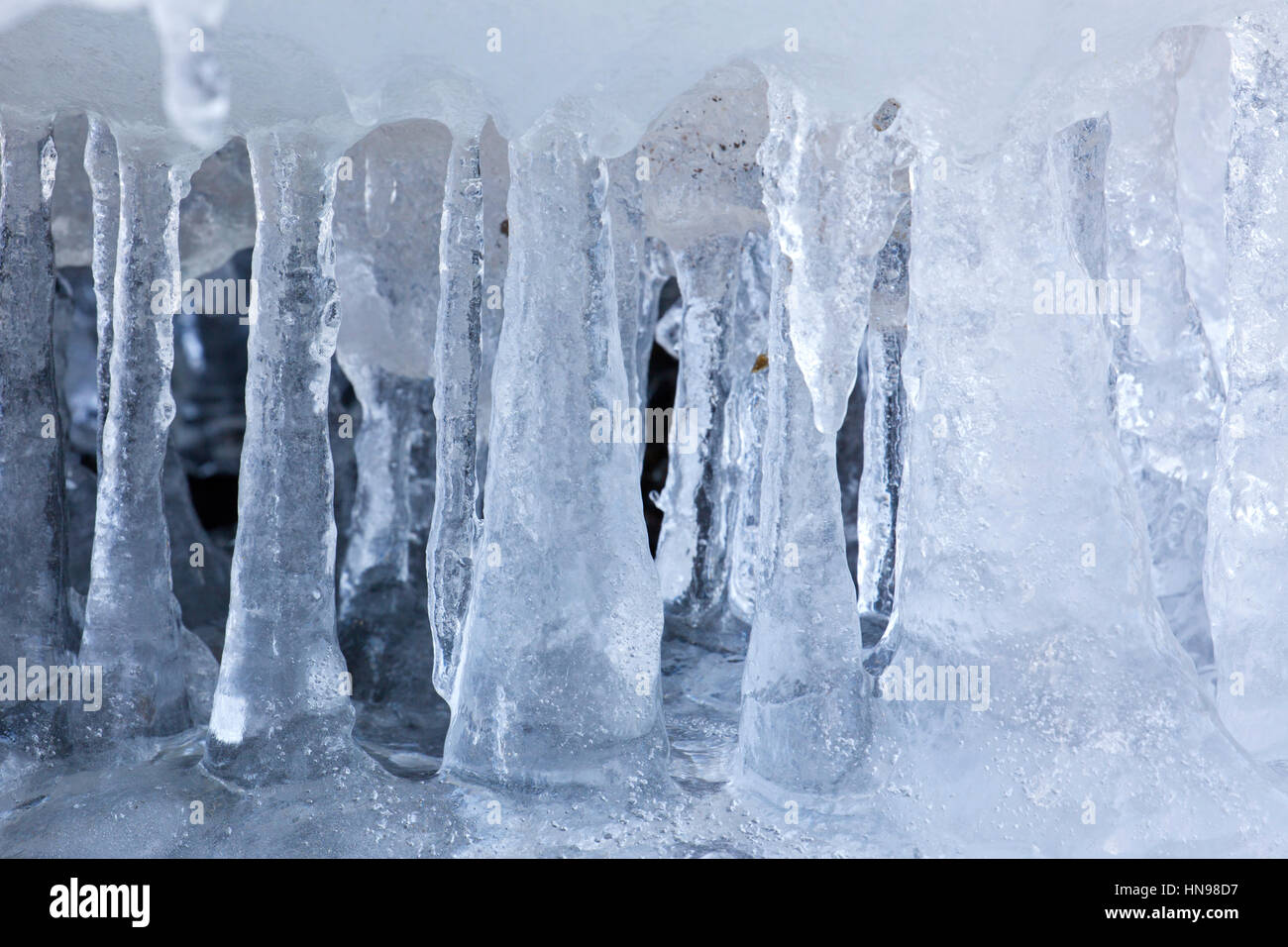 Ice formations and icicles formed by frost and freezing cold temperatures over running water of stream Stock Photo