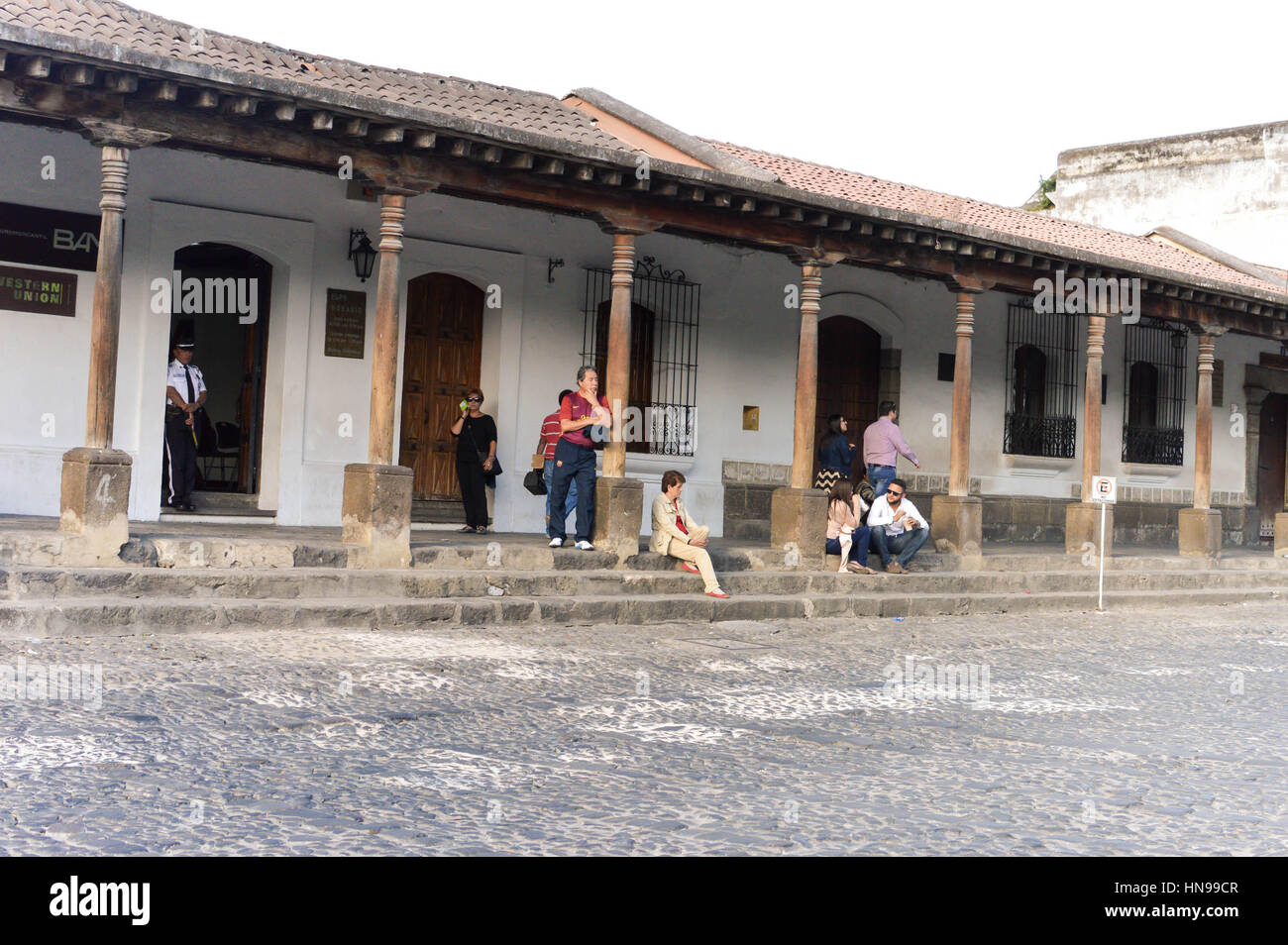 Antigua, Guatemala - February 15, 2015: Tourists and locals relax by one of the colonial buildings on the main plaza of Antigua, Guatemala Stock Photo