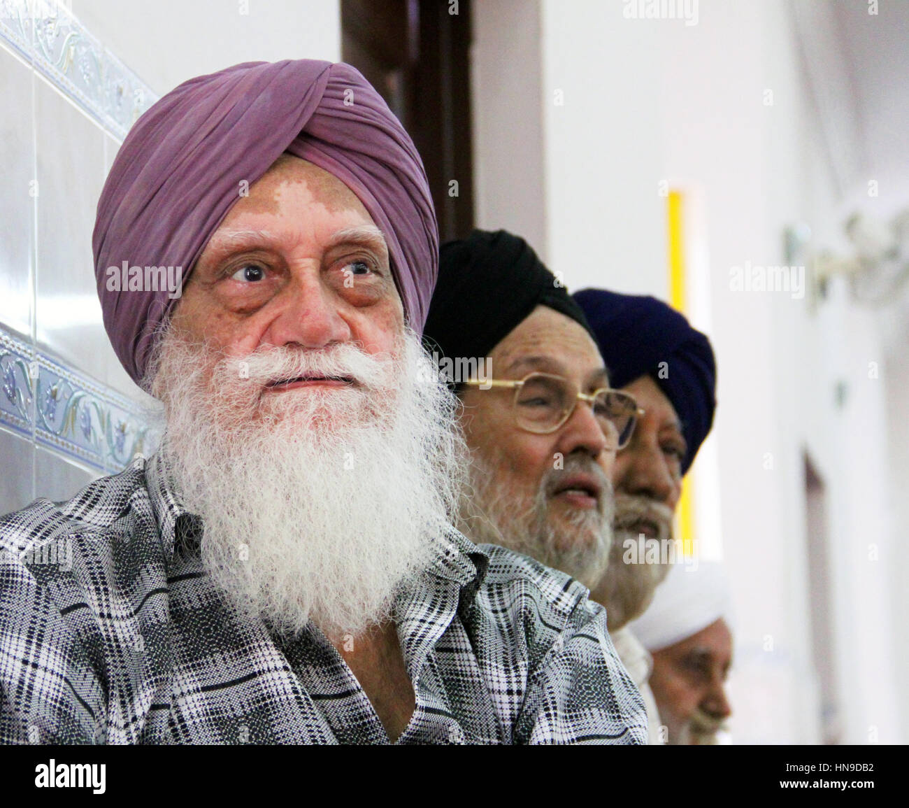 An elderly Indian Sikh man with a long white beard wearing a turban with the vitiligo skin disorder at a Sikh Wedding in Malaysia Stock Photo
