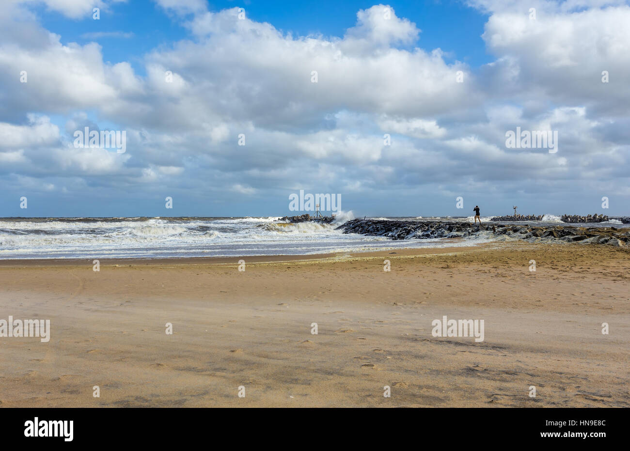 The New Jersey shore at manasquan Inlet. The ocean is rough as there is a storm out to sea. There is a lone person standing on a rock jetty. Stock Photo