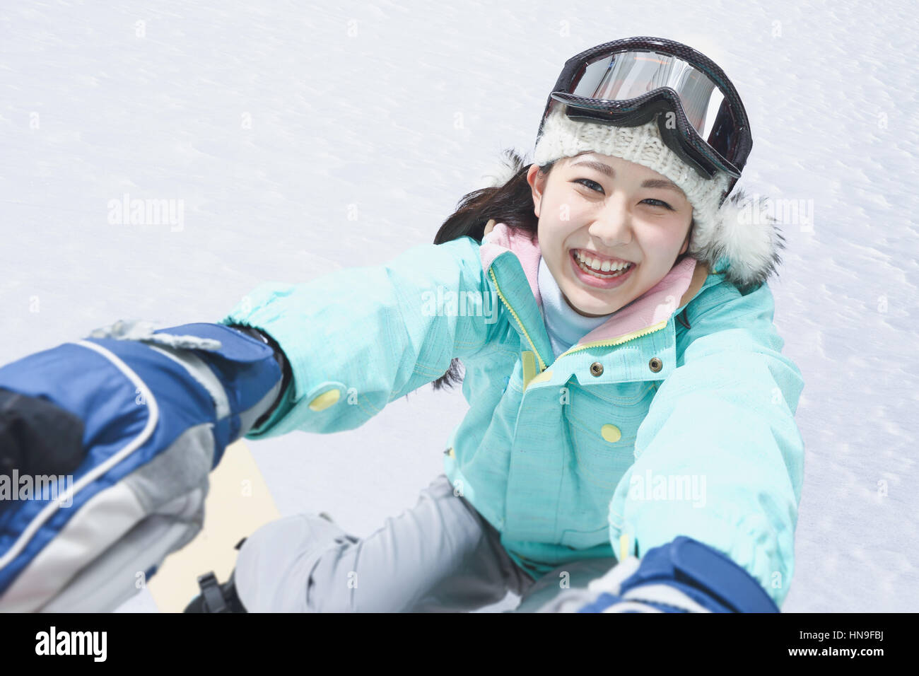Young Japanese woman snowboarding Stock Photo