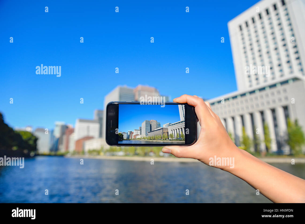 Japanese woman using augumented reality app on smartphone downtown Tokyo, Japan Stock Photo
