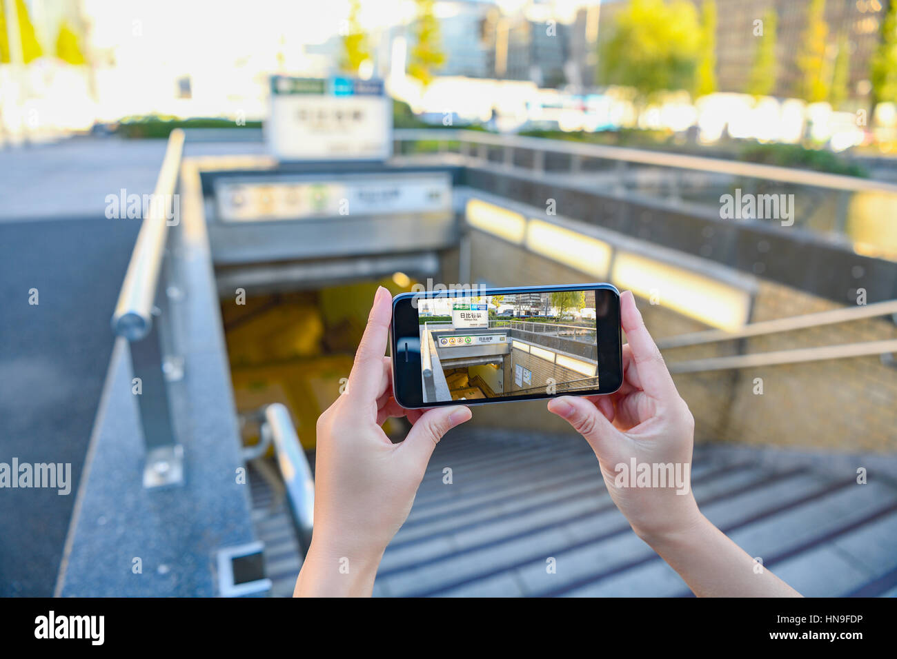 Japanese woman using augumented reality app on smartphone downtown Tokyo, Japan Stock Photo