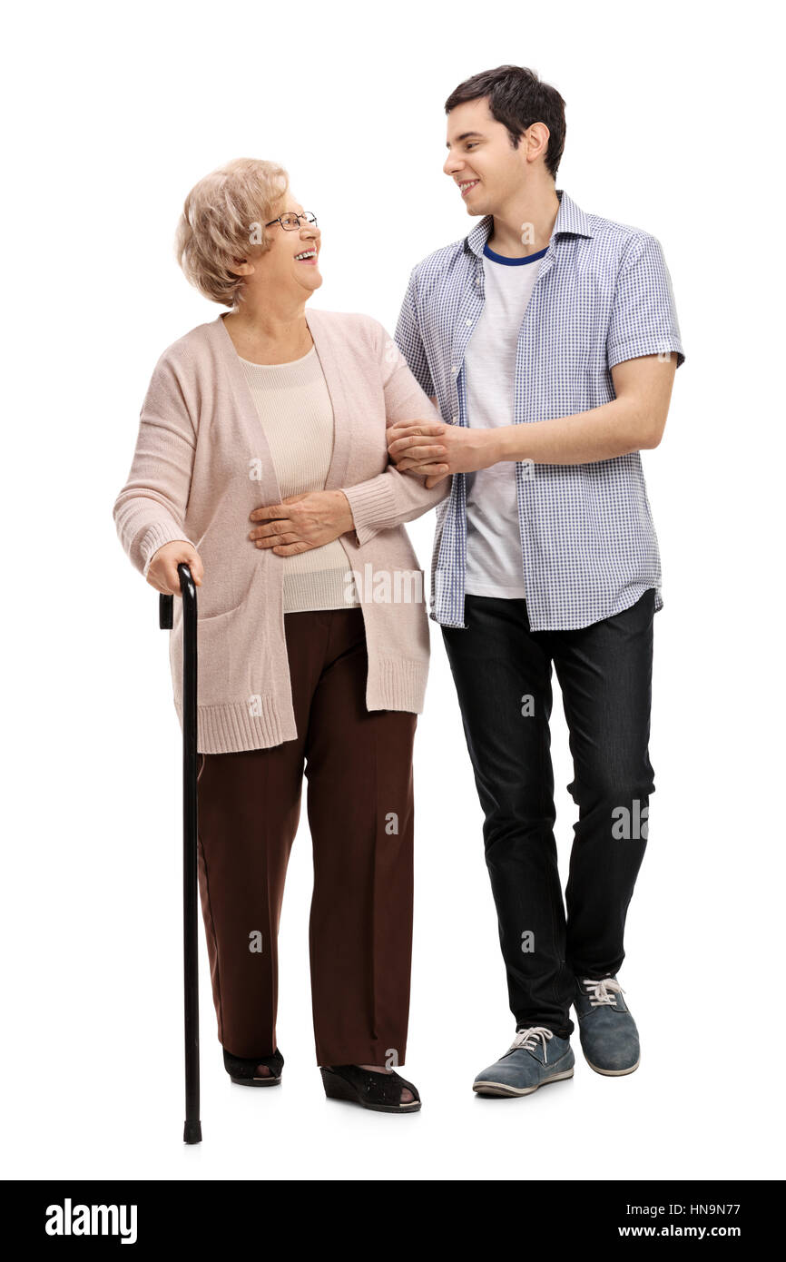 Full length portrait of a young man helping a mature woman with a walking cane isolated on white background Stock Photo