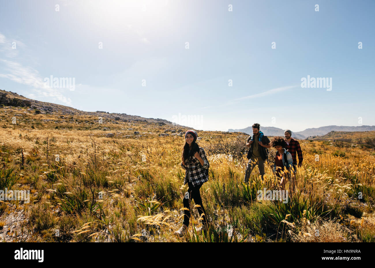 Group of friends are hiking in mountain on a sunny day. Four young ...