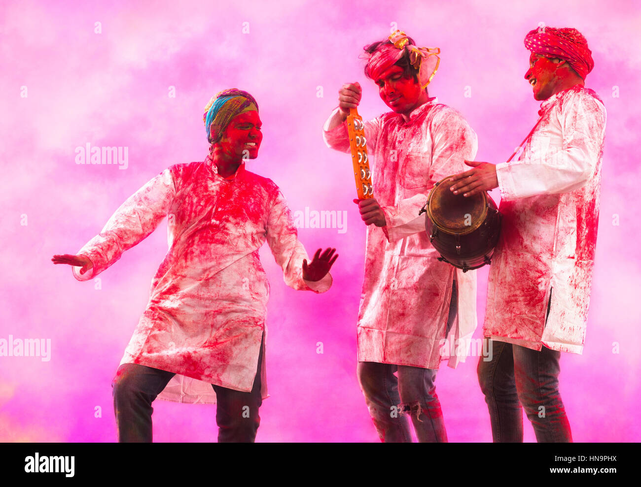 Three Young Indian men With Colored Face Dancing During Holi Color festival Stock Photo