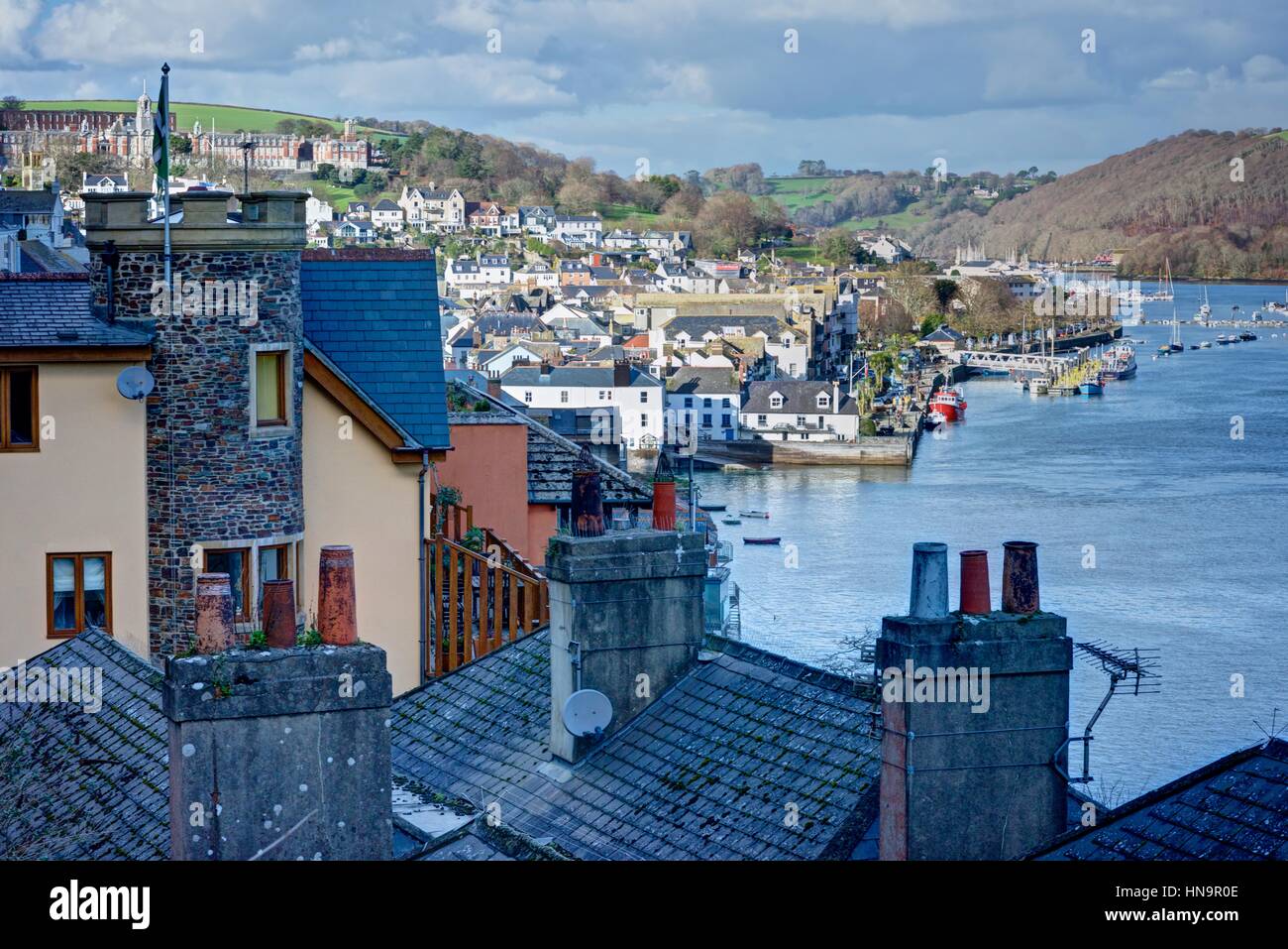 Dartmouth Estuary photographed from between interesting house roof chimneys looking across to the Naval College and the town on a sunny winters day. Stock Photo