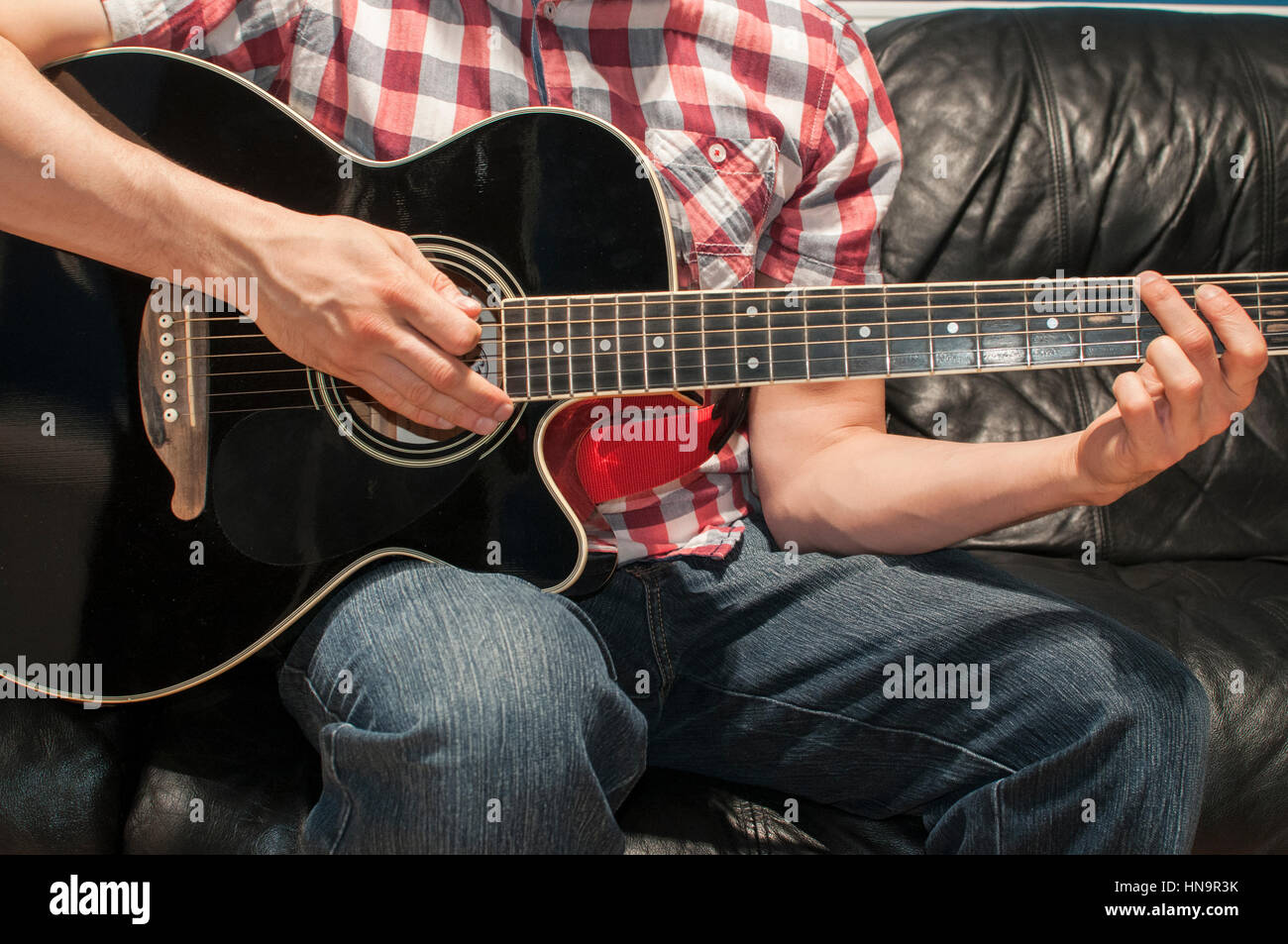 Playing chords on a black acoustic guitar Stock Photo Alamy