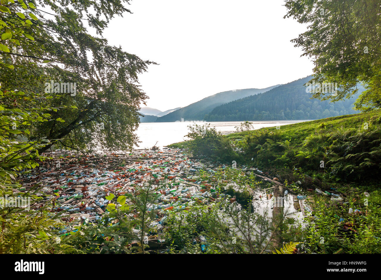 Big lake in mountains with lot of garbage trash cans and bottles 