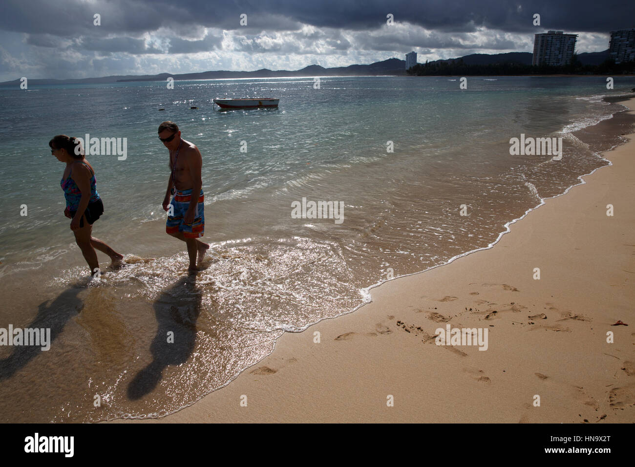 Older couple walking on tropical beach, Luquillo, Puerto Rico Stock Photo