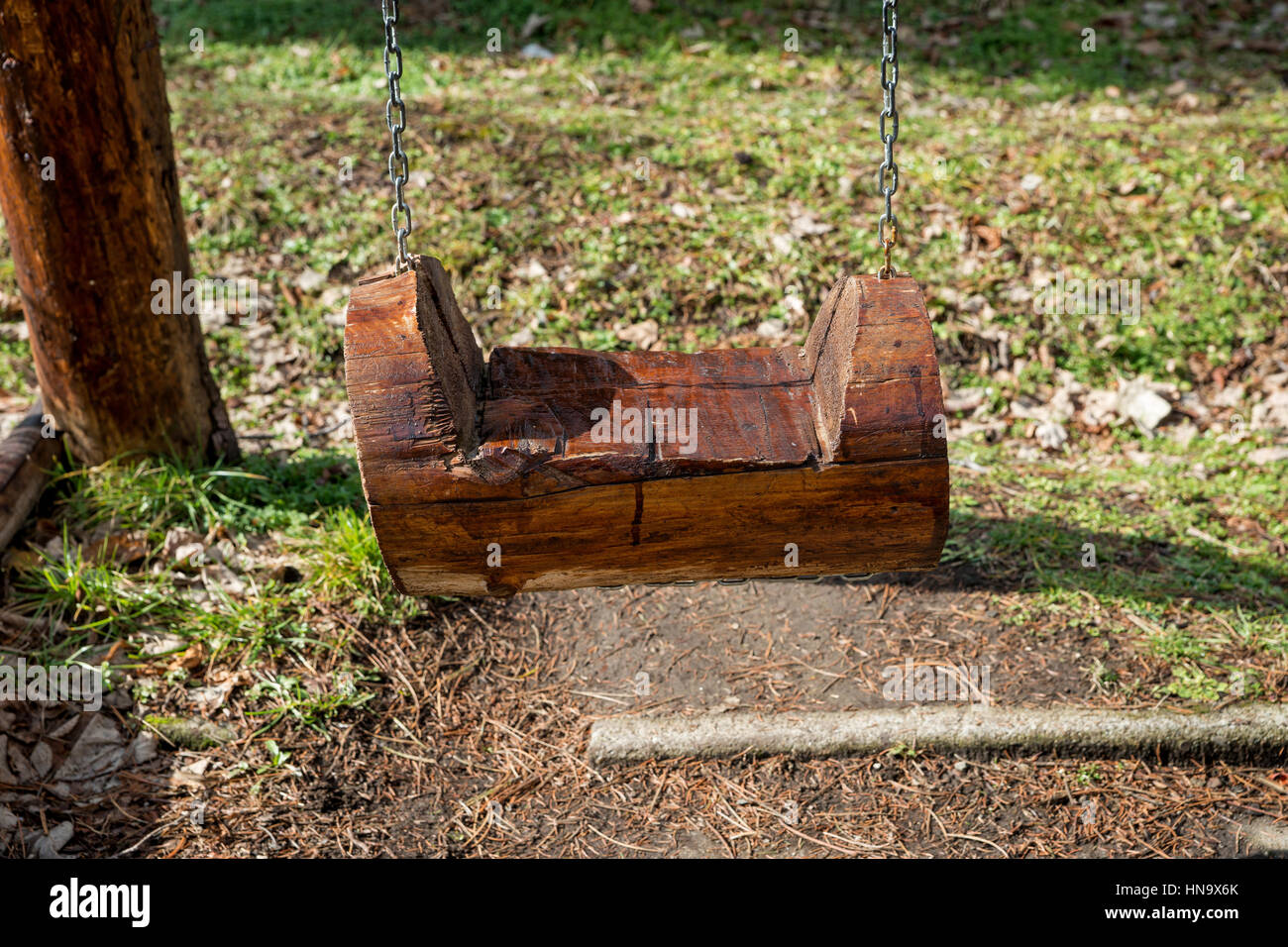 The seat of a swing made of tree trunks hung on chains Stock Photo