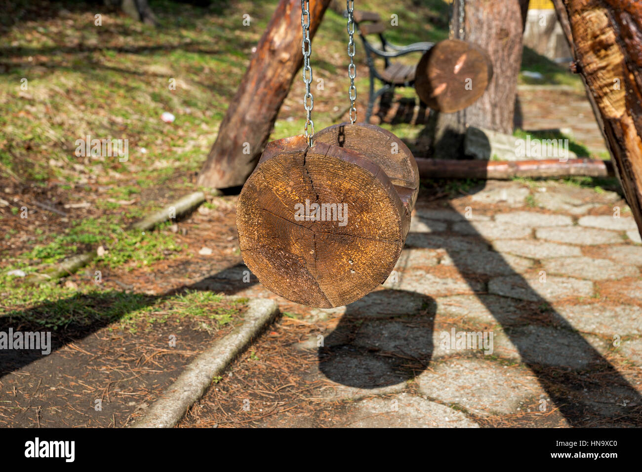 The seat of a swing made of tree trunks hung on chains Stock Photo