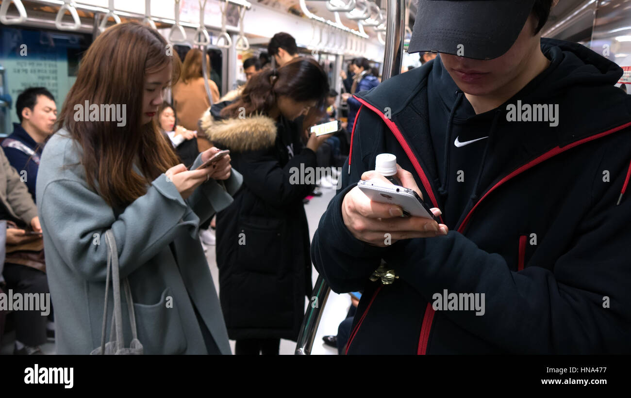 Asian people traveling on subway train and using mobile phone in Seoul, South Korea, Asia. Korean youth with smartphone for internet and social media Stock Photo