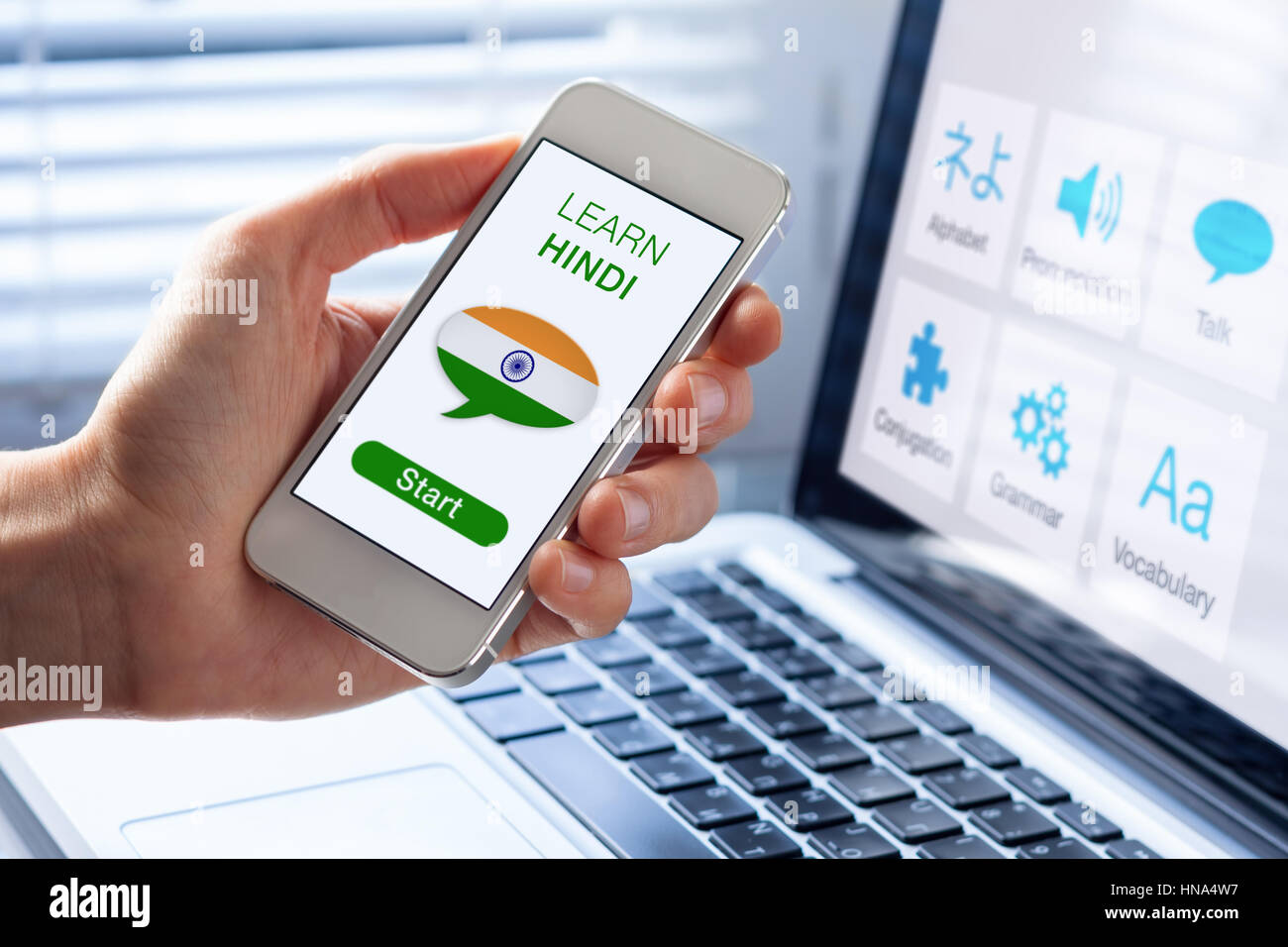 Learn Hindi language online concept with a person showing e-learning app on mobile phone with the flag of India Stock Photo
