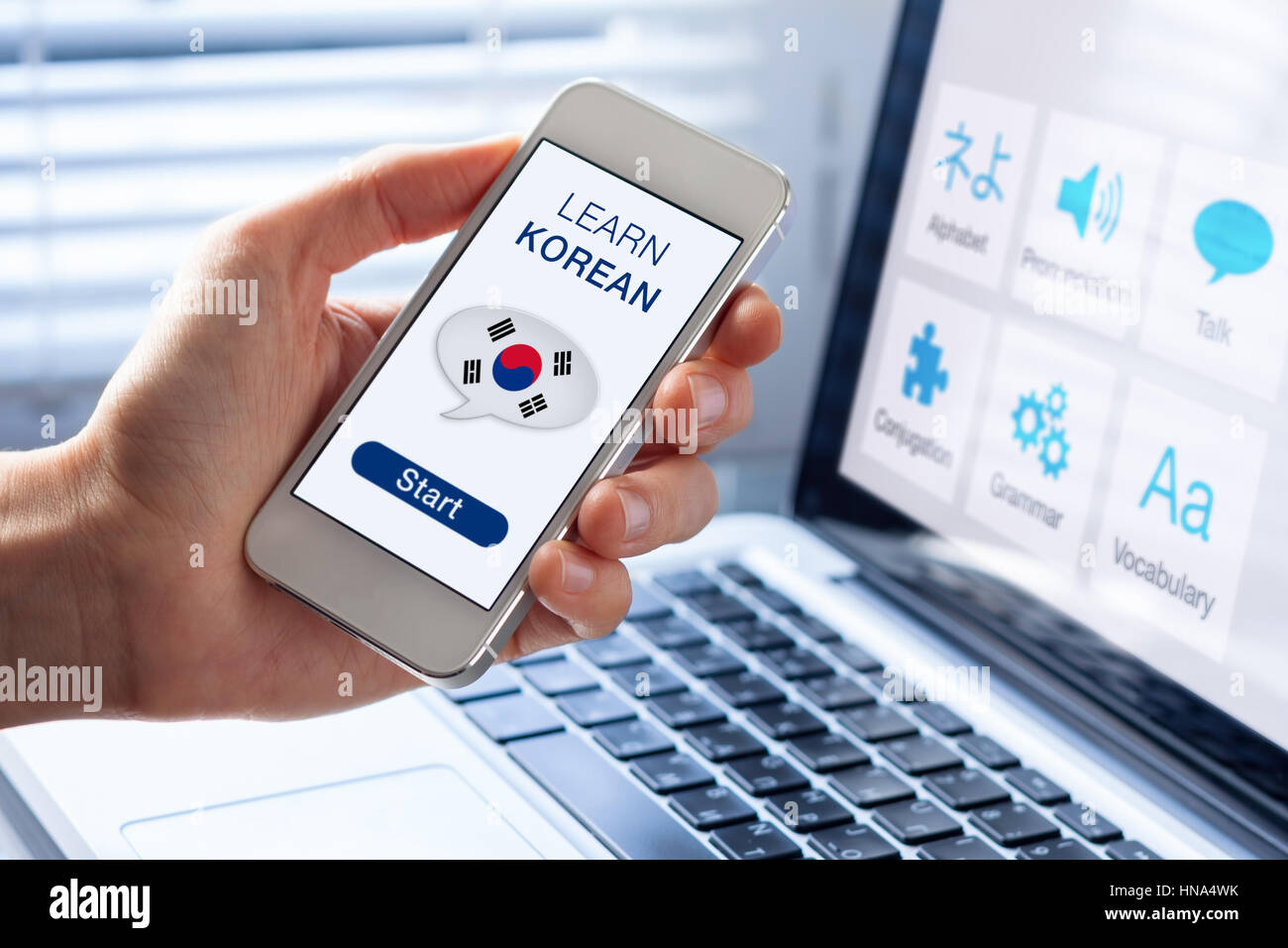 Learn Korean language online concept with a person showing e-learning app on mobile phone with the flag of South Korea Stock Photo