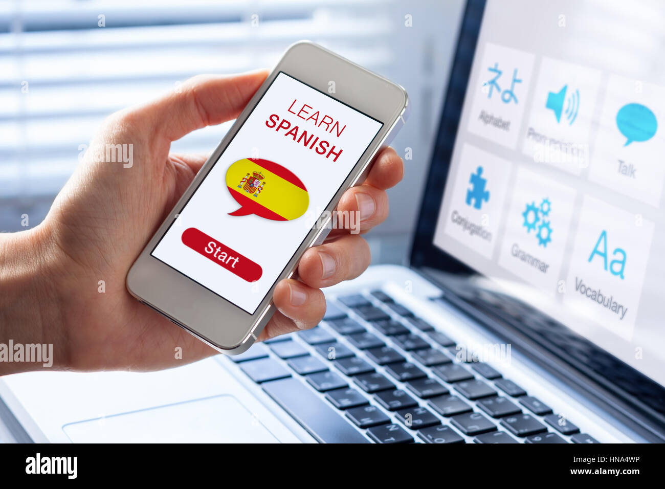 Learn Spanish language online concept with a person showing e-learning app on mobile phone with the flag of Spain Stock Photo