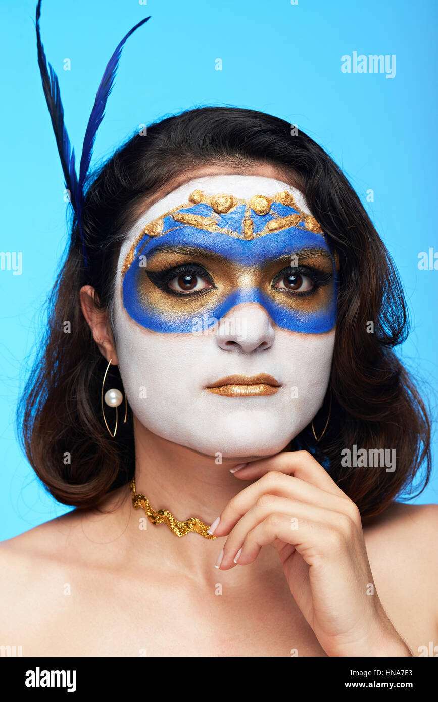 portrait of young women in painted blue mask isolated on blue background Stock Photo