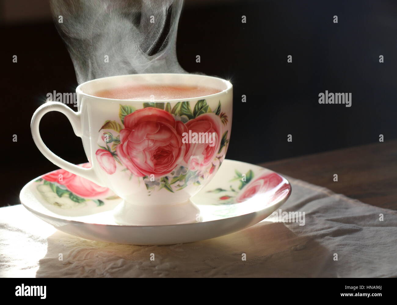 Steaming hot cup of tea in a bone china cup with cottage roses Stock