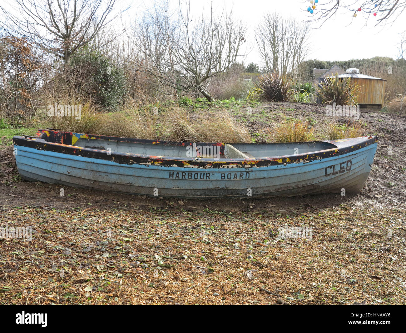Old blue wooden rowing boat ready to be upcycled in school garden project Stock Photo