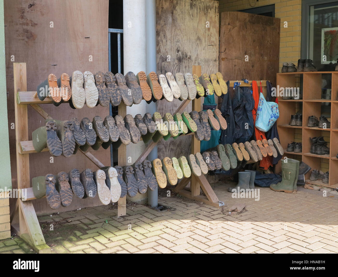 Rows of wellies and outdoor shoes belonging to a school children's gardening club Stock Photo