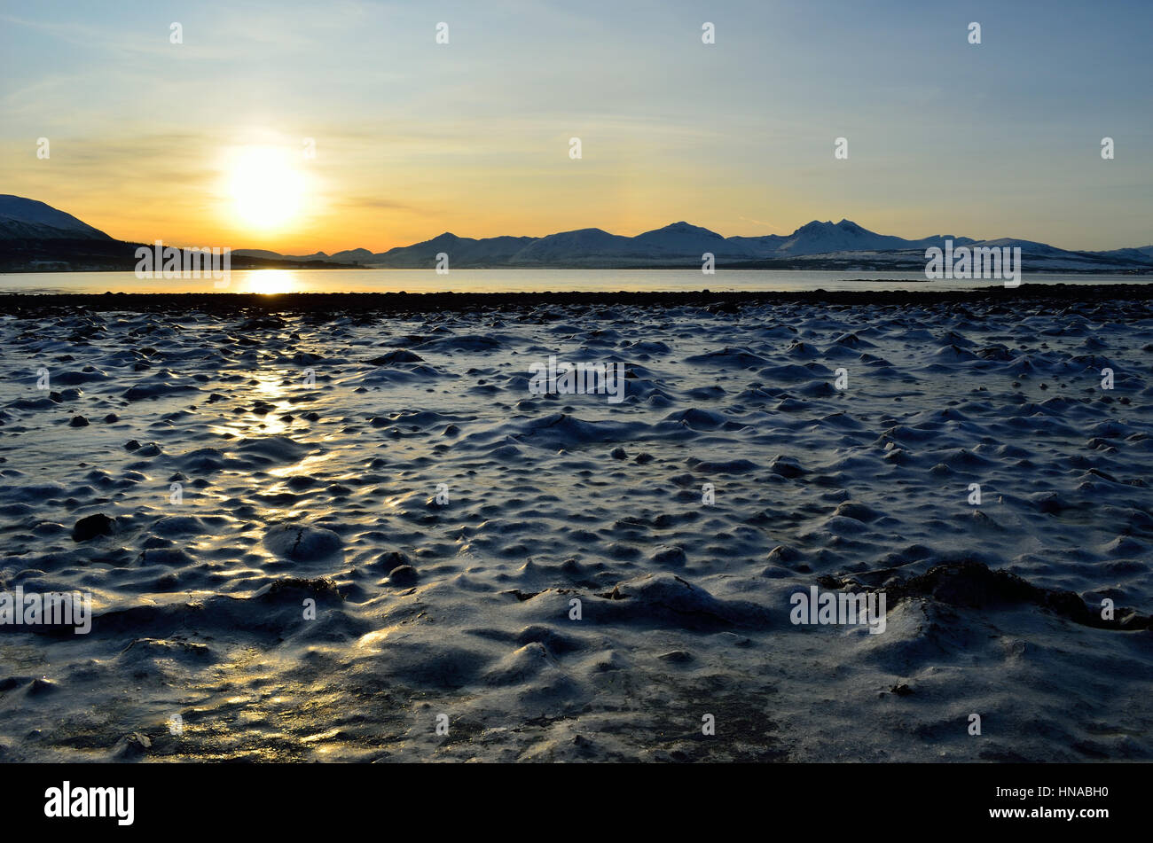 golden sunrise over blue fjord and snowy mountain with reflection on ...
