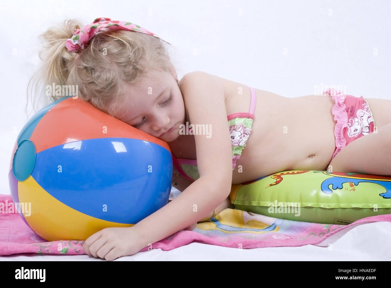 Maedchen im Bikini schlaeft auf Wasserball - girl in bikini sleeping on water ball Stock Photo