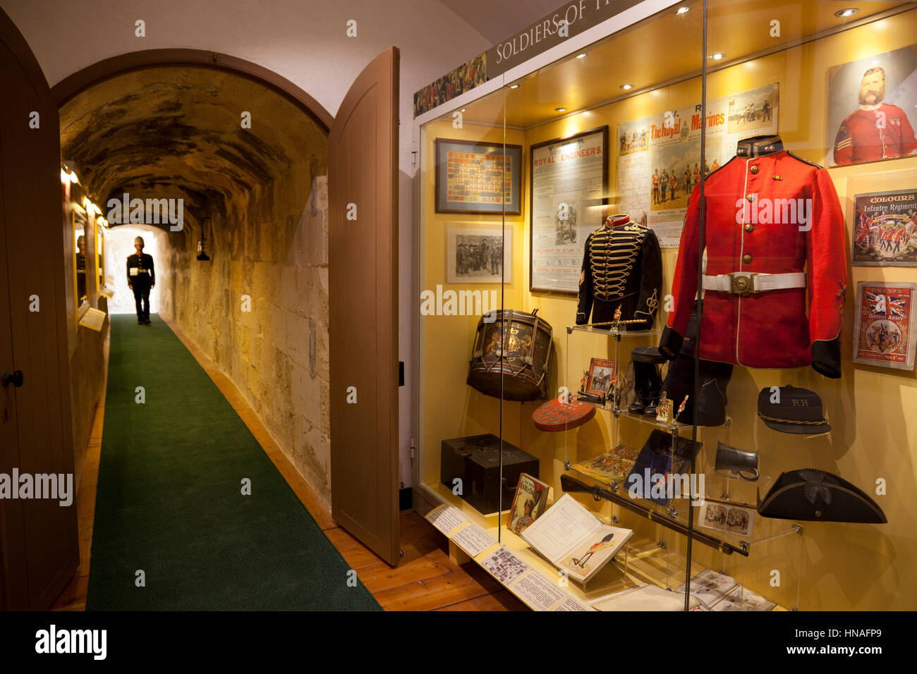A site guide in historial British military uniform walks down a corridor towards the displays of nineteenth century British military artifacts and col Stock Photo
