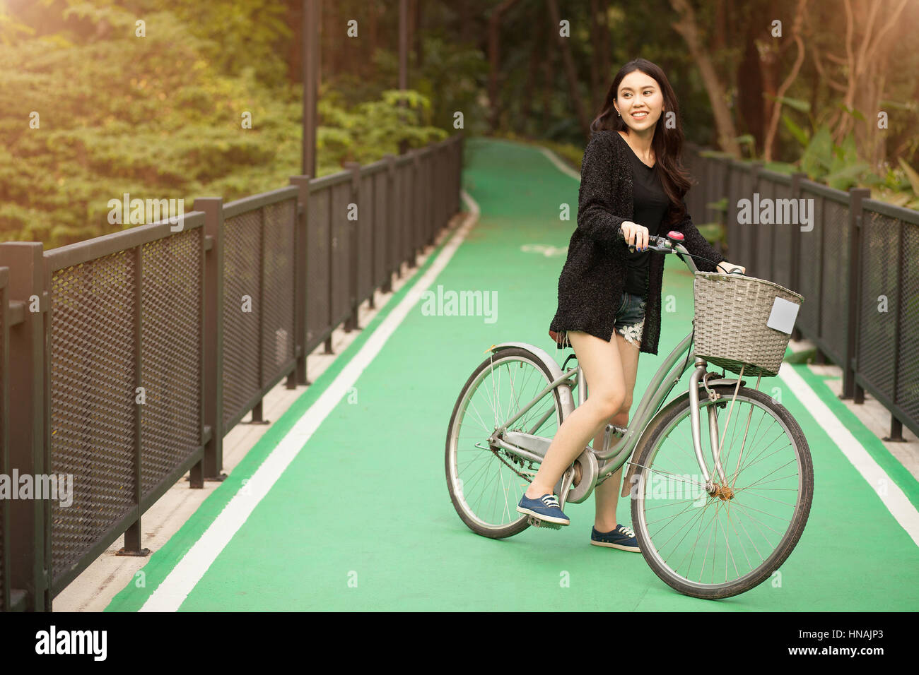 Pretty Thai girl rides bicycle at the park Stock Photo - Alamy