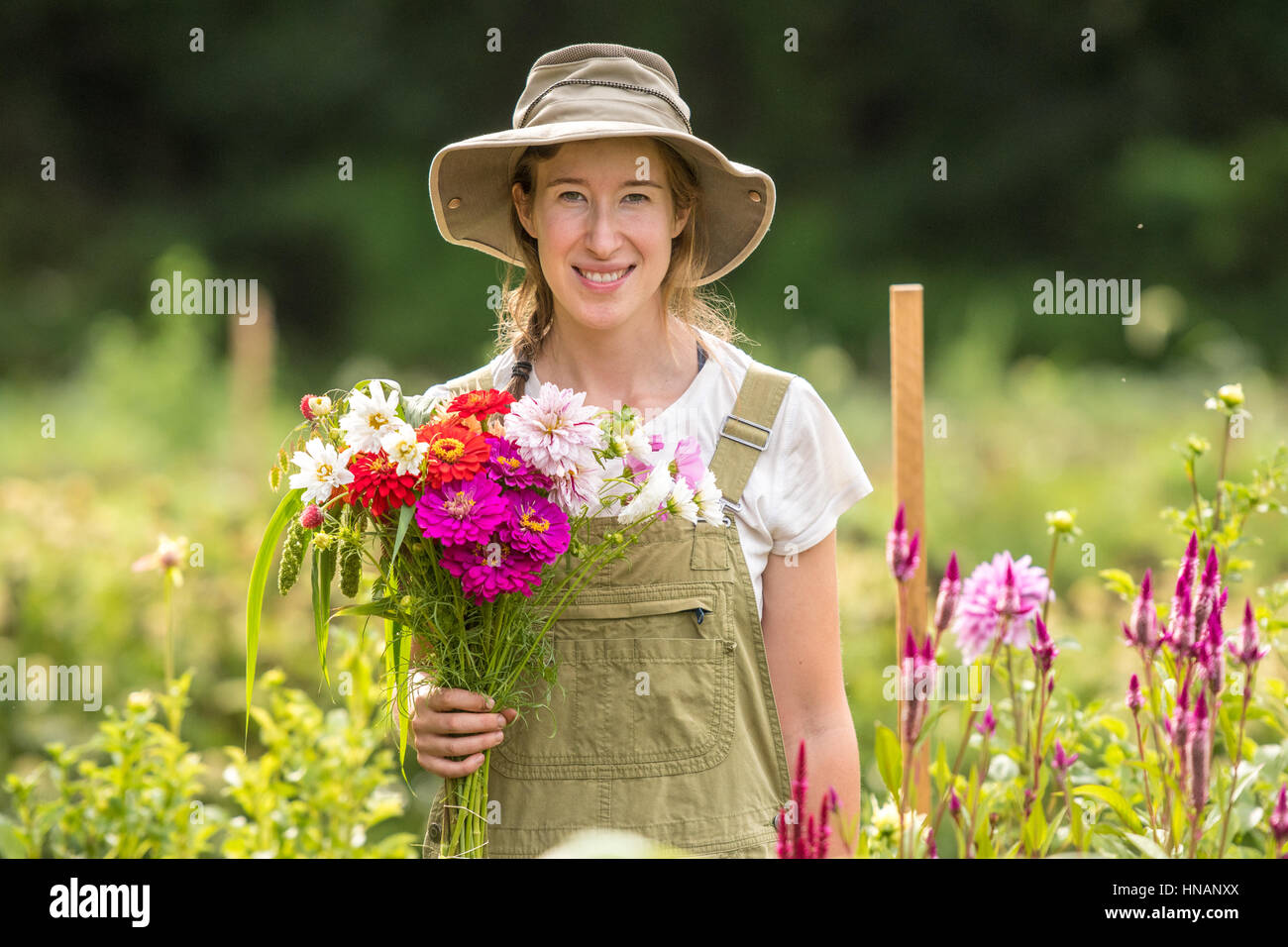A woman poses with a bouquet of freshly cut flowers from a garden on a farm in rural Maryland. Stock Photo