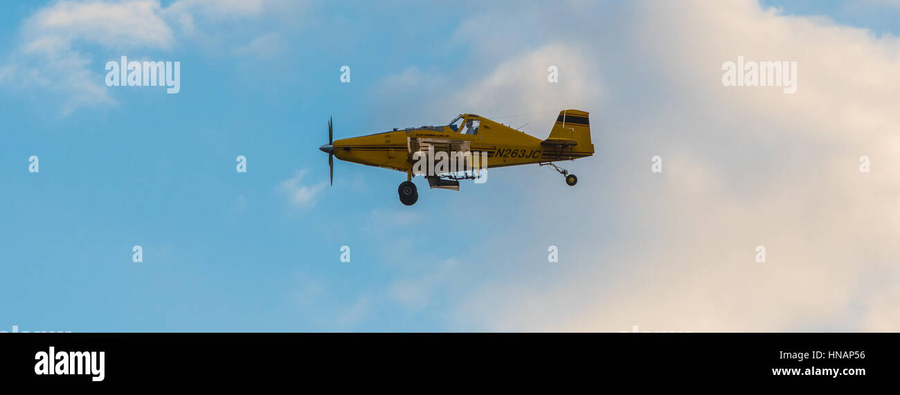 A crop-duster plane flies over a farm and coats crops with pesticides in Secretary, Maryland. Stock Photo