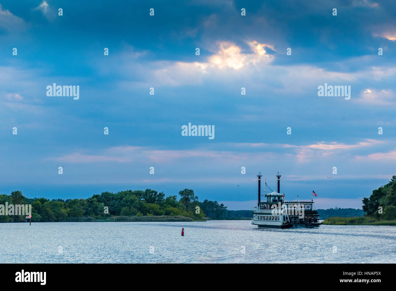 A paddlewheel riverboat travels through the Chesapeake bay at sunset in Secretary, Maryland. Stock Photo