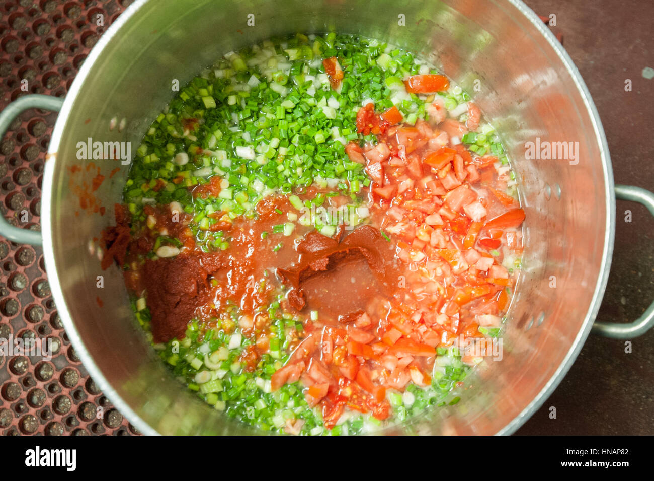 A pot full of tomatoes, spices, and other fresh greens is about to simmer at Gertrude's restaurant located in Baltimore, Maryland. Stock Photo