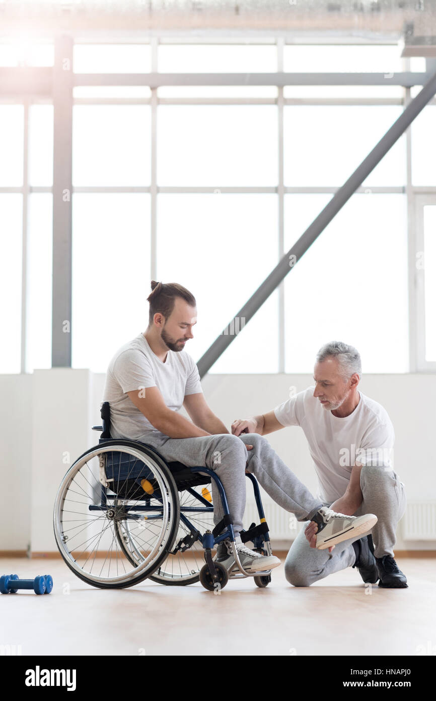 Aged physical therapist helping the disabled patient in the gym Stock Photo