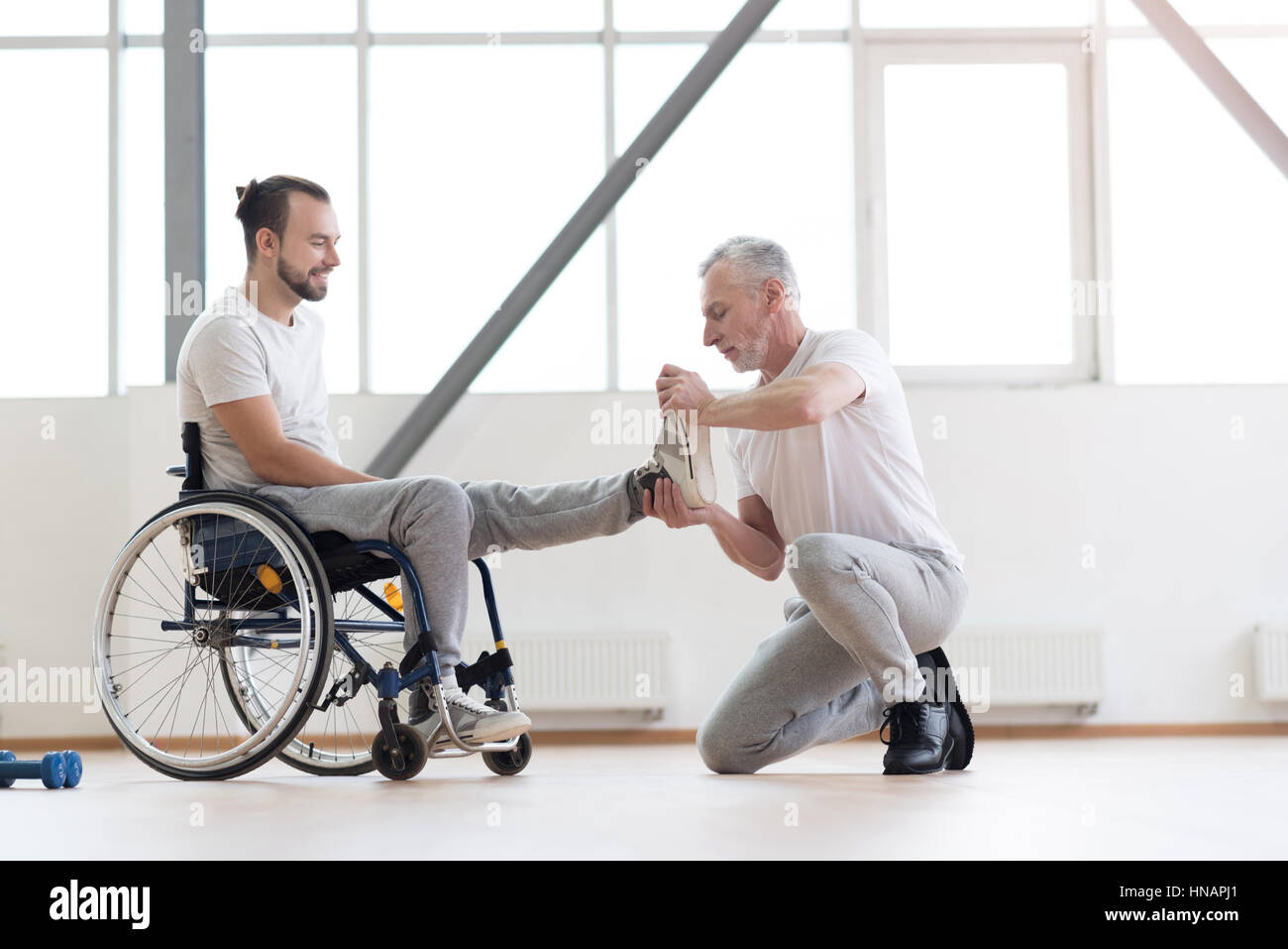 Aged orthopedist working with disabled patient in the gym Stock Photo