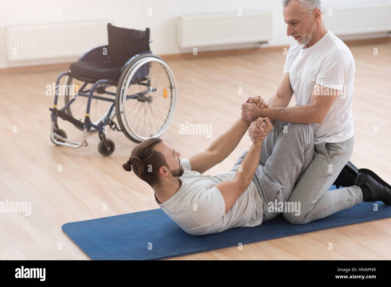 Strong aged orthopedist assisting the disabled in the gym Stock Photo