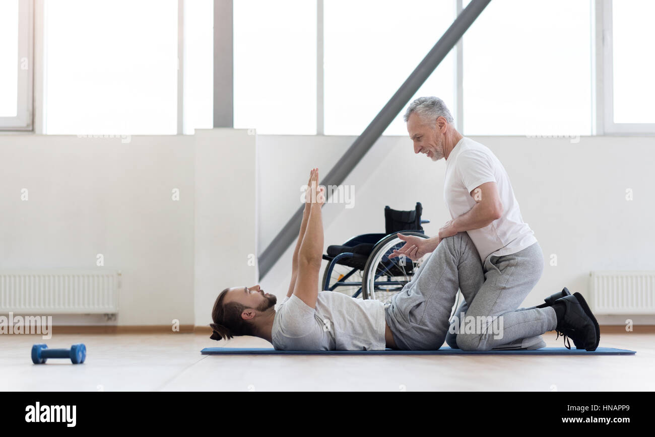 Positive physical therapist assisting the handicapped in the gym Stock Photo