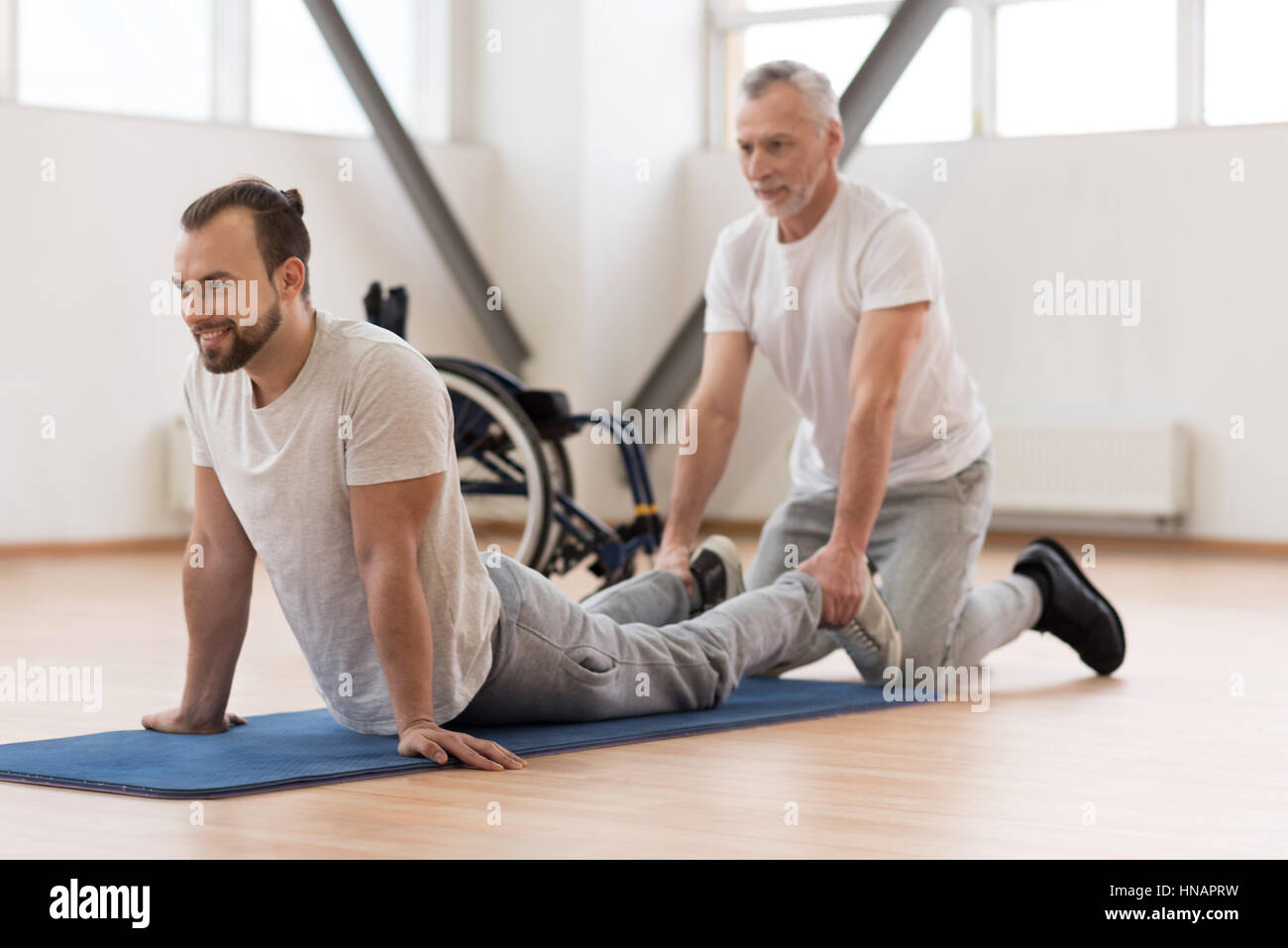 Cheerful physical therapist stretching the handicapped in the gym Stock Photo