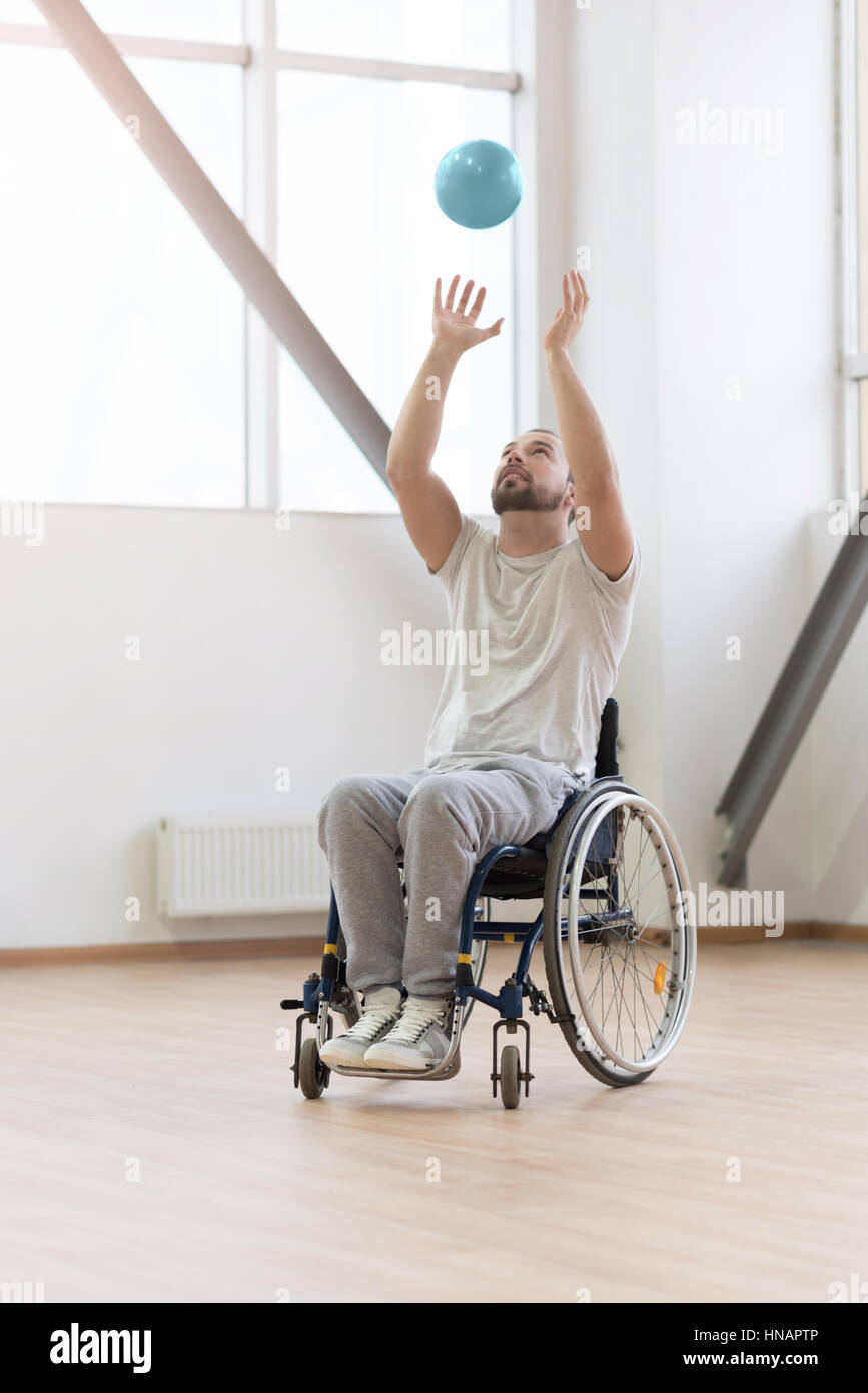 Positive young handicapped playing the ball in the gym Stock Photo