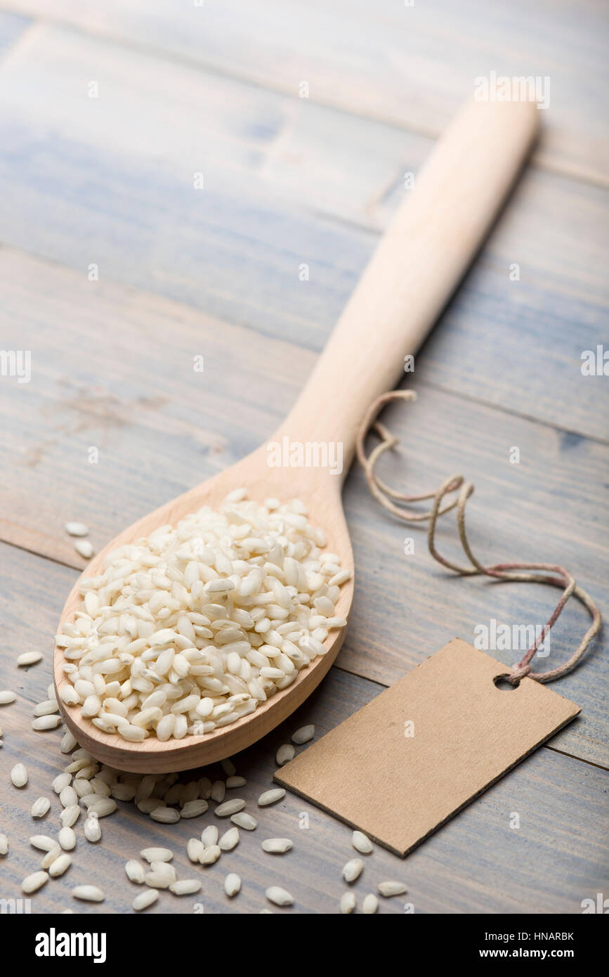 heap of white rice in wooden spoon on table with label for text. Stock Photo