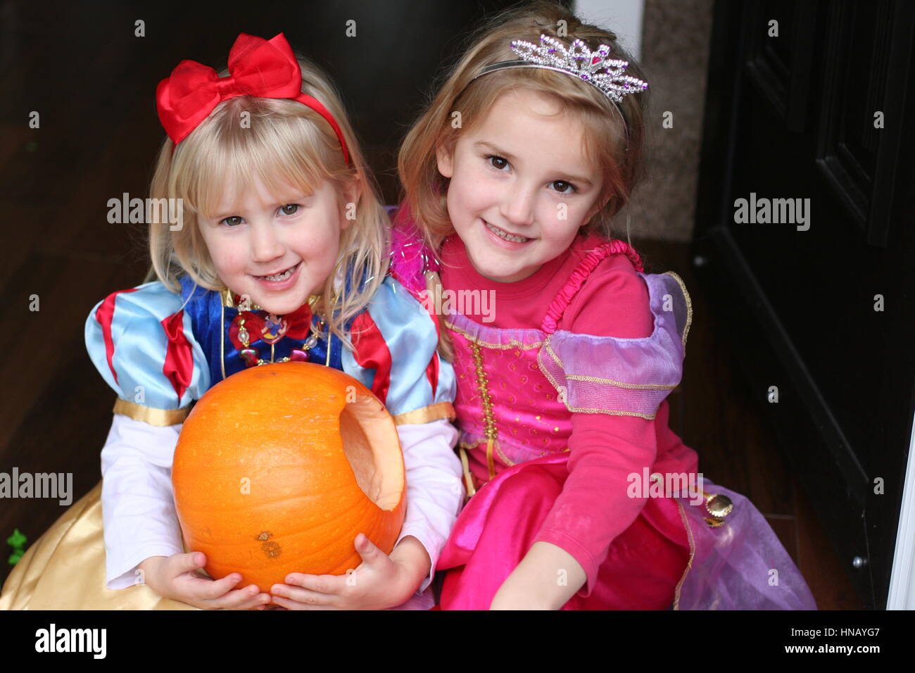 Blonde Children kids holding a heavy carved pumpkin wearing princess  costumes, snow white Halloween, Trick or Treat siblings sisters, disney  dresses Stock Photo - Alamy