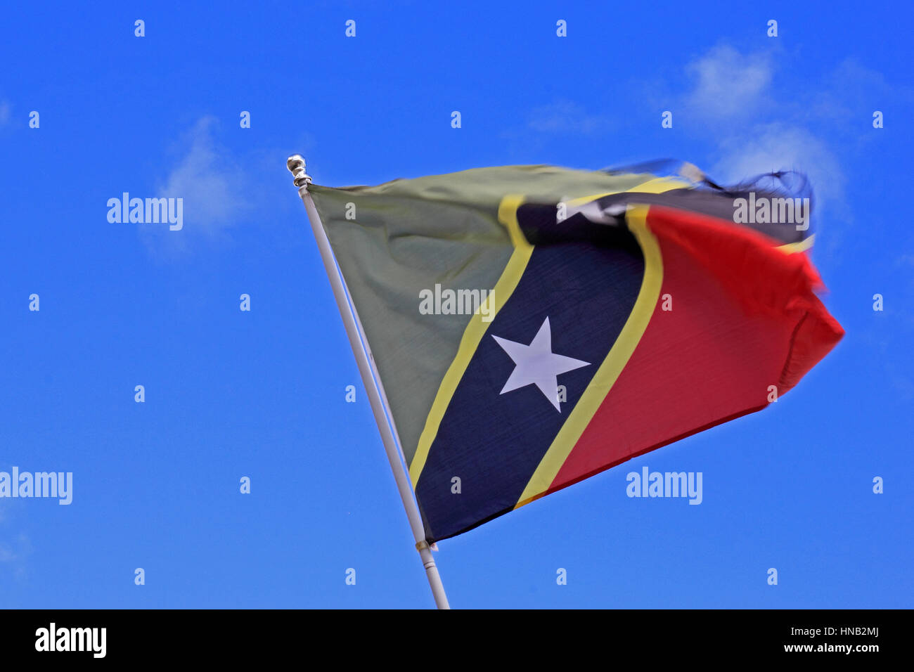 National flag of St Kitts flying against a blue sky Stock Photo