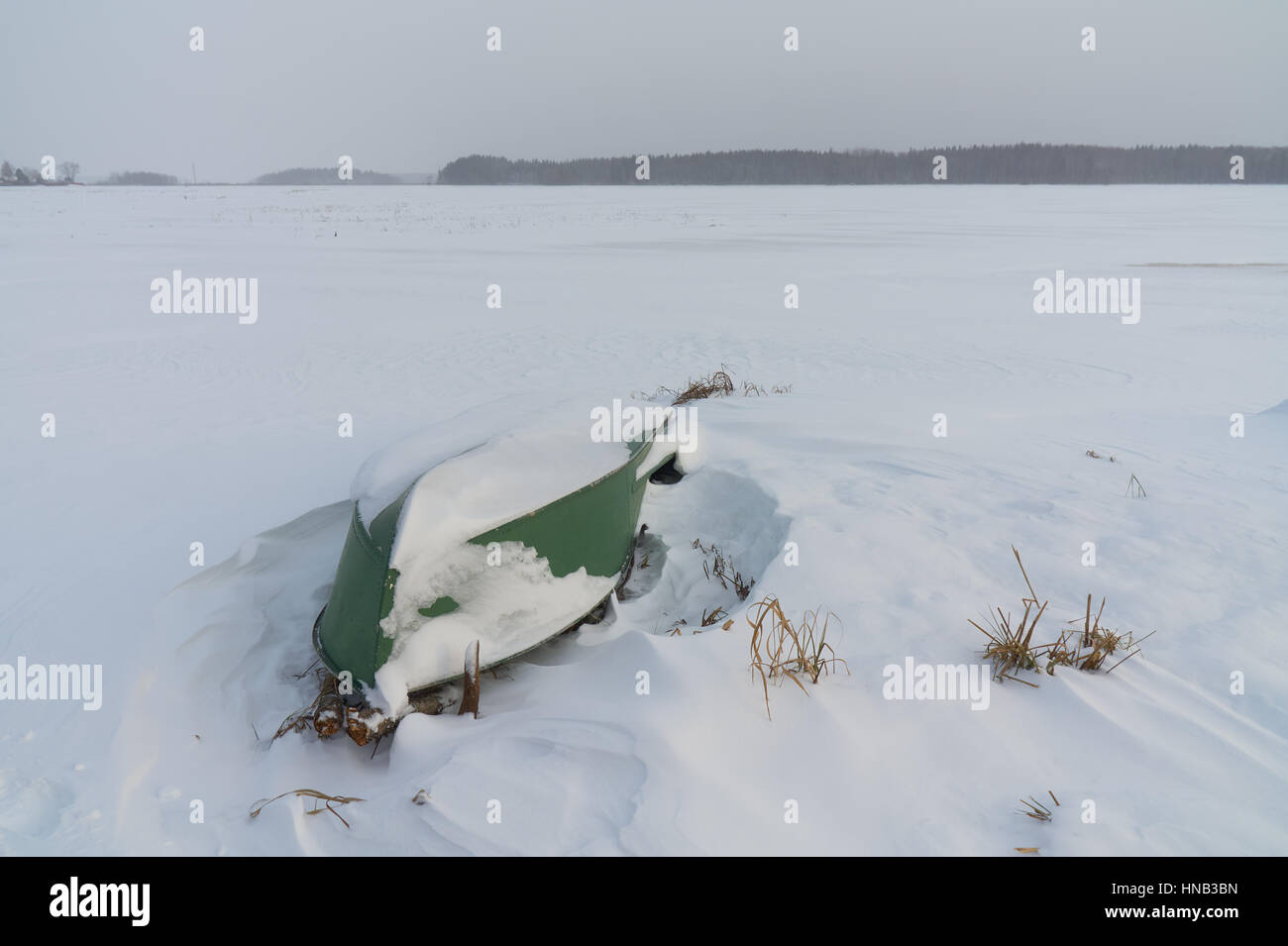 Winter landscape with green flipped over boat on the foreground. Peno lake, Tver oblast, Russia. Stock Photo
