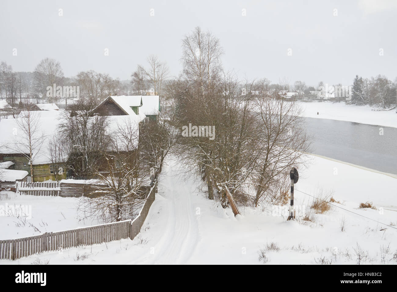 Winter view on russian town Peno, Tver oblast, Russia. The river is upper Volga. There is a fisherman doing ice fishing on the right. Stock Photo