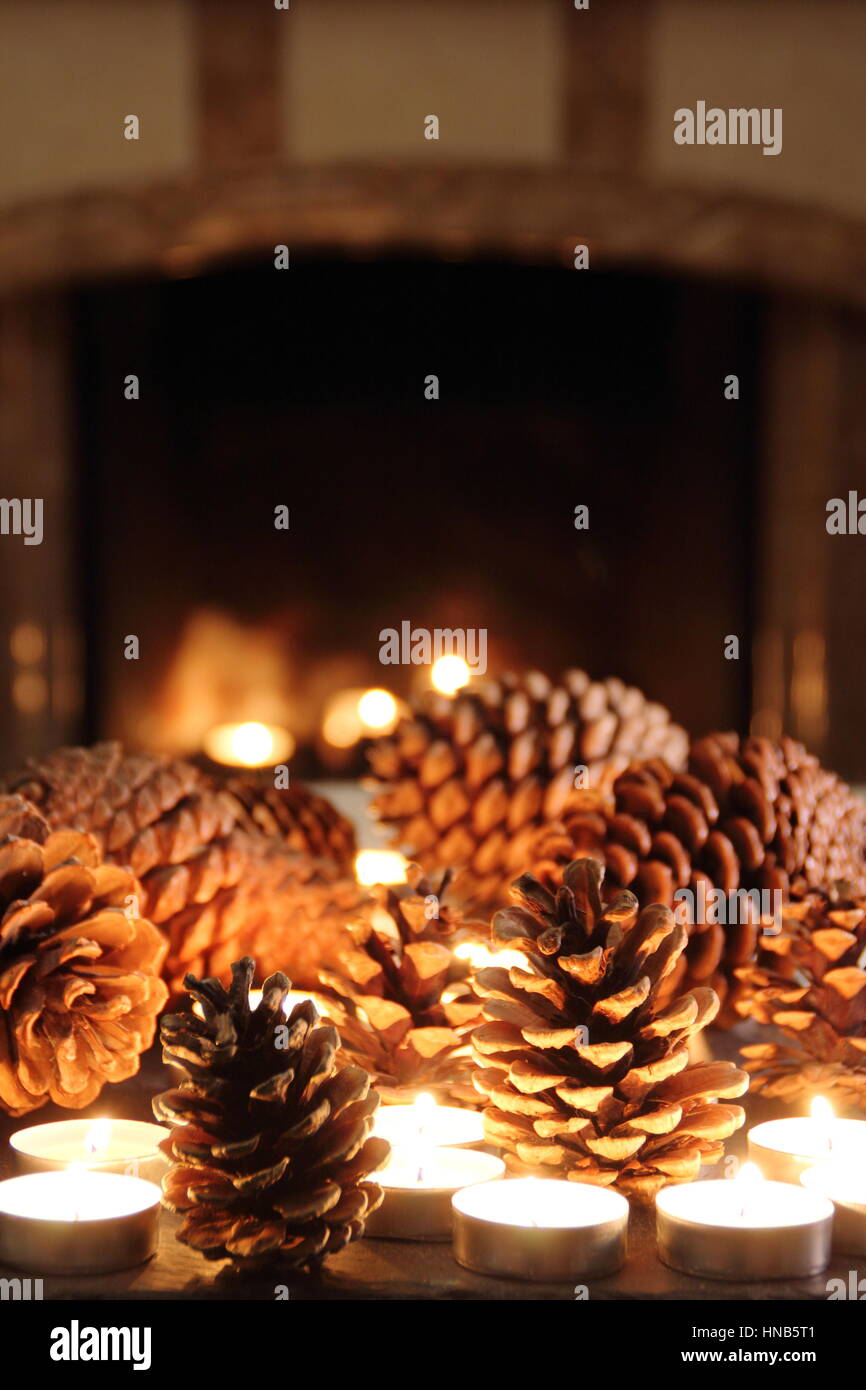 Pine cones and candle light festive slate table top display in a cosy fireside setting of an English home at winter Stock Photo